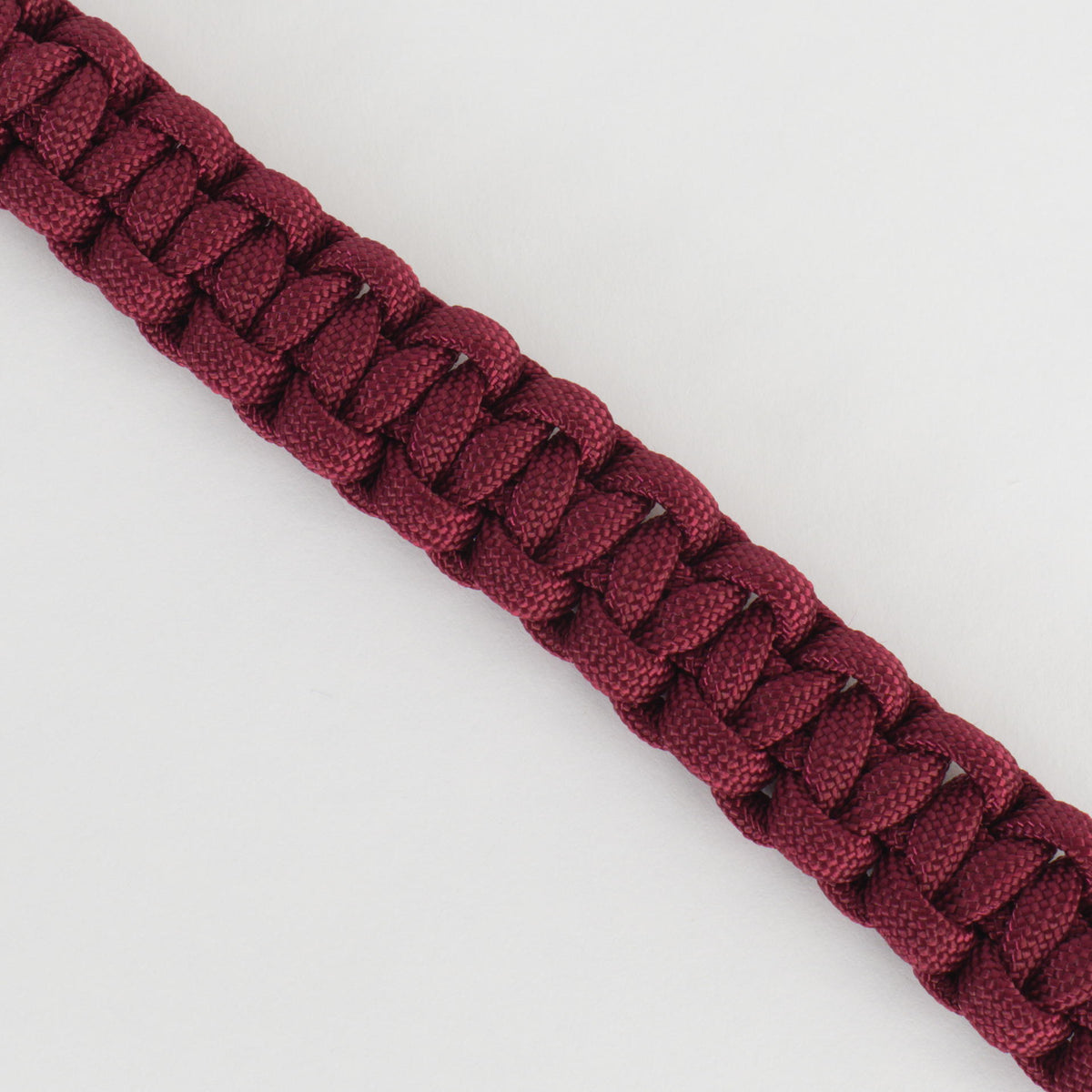 A close-up of a dark burgundy braided cord or strap, shown diagonally on a plain white background.