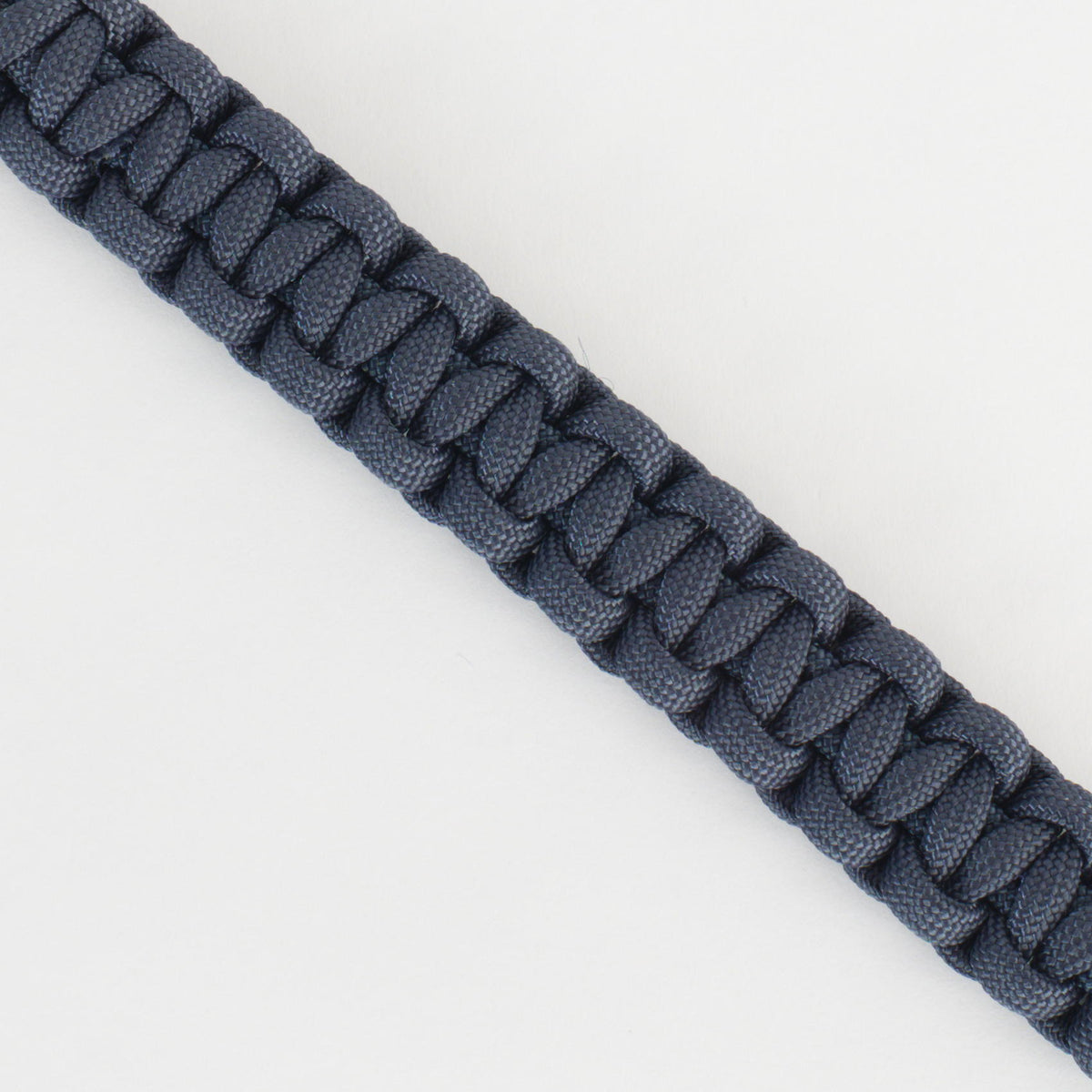 A close-up of a dark navy blue braided cord or strap, shown diagonally against a plain white background.