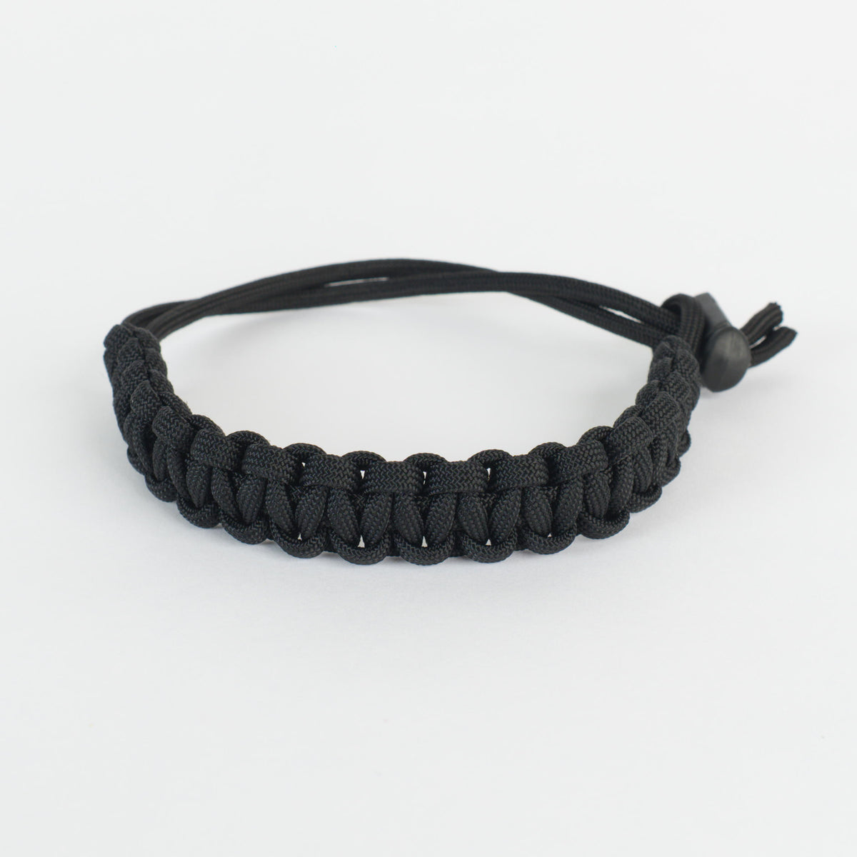 A black paracord bracelet with an adjustable sliding knot closure, shown on a clean white background.