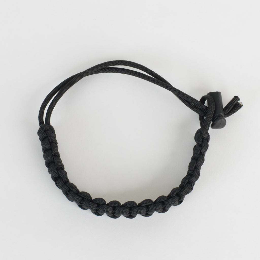 A black paracord bracelet with a toggle clasp, photographed on a clean white background.