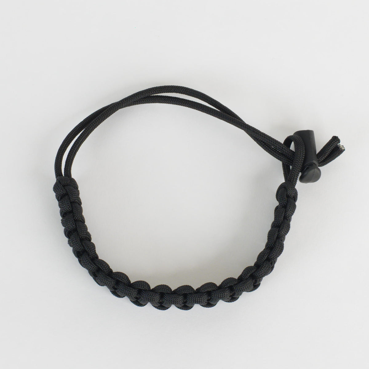 A black paracord bracelet with a toggle clasp, photographed on a clean white background.