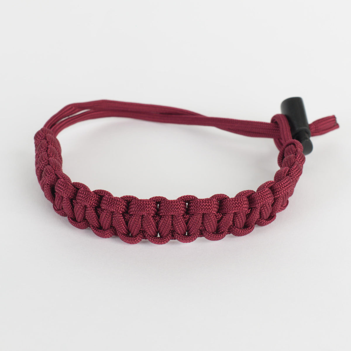 A burgundy paracord bracelet with a black toggle clasp, photographed on a clean white background.