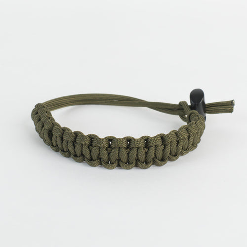 An olive green paracord bracelet with a black plastic toggle clasp, photographed on a clean white background.
