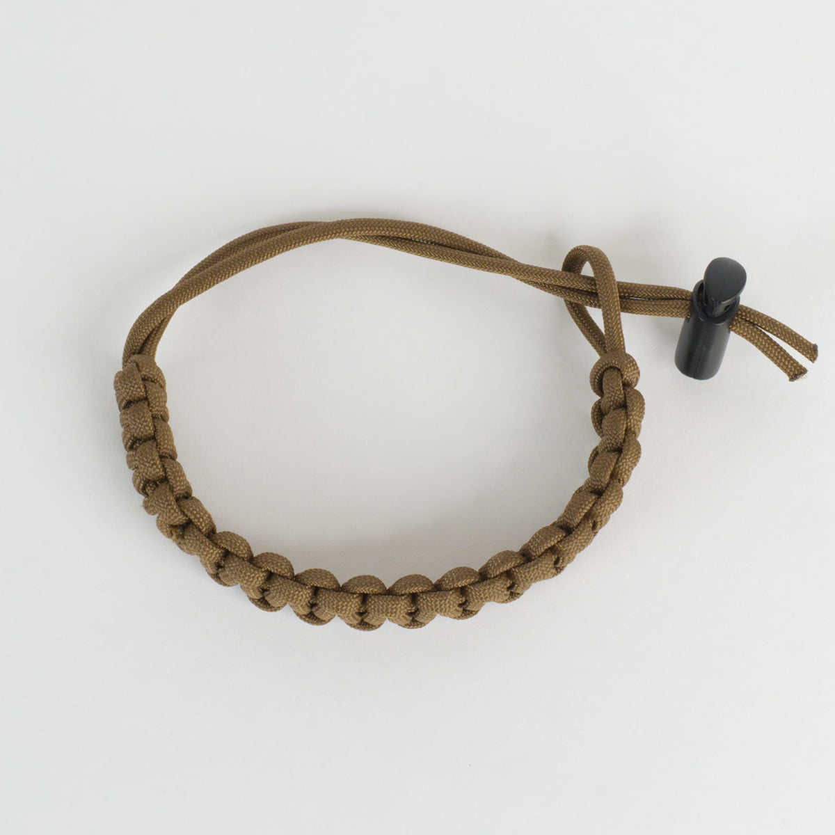 A brown paracord bracelet with a black toggle clasp, photographed on a clean white background.