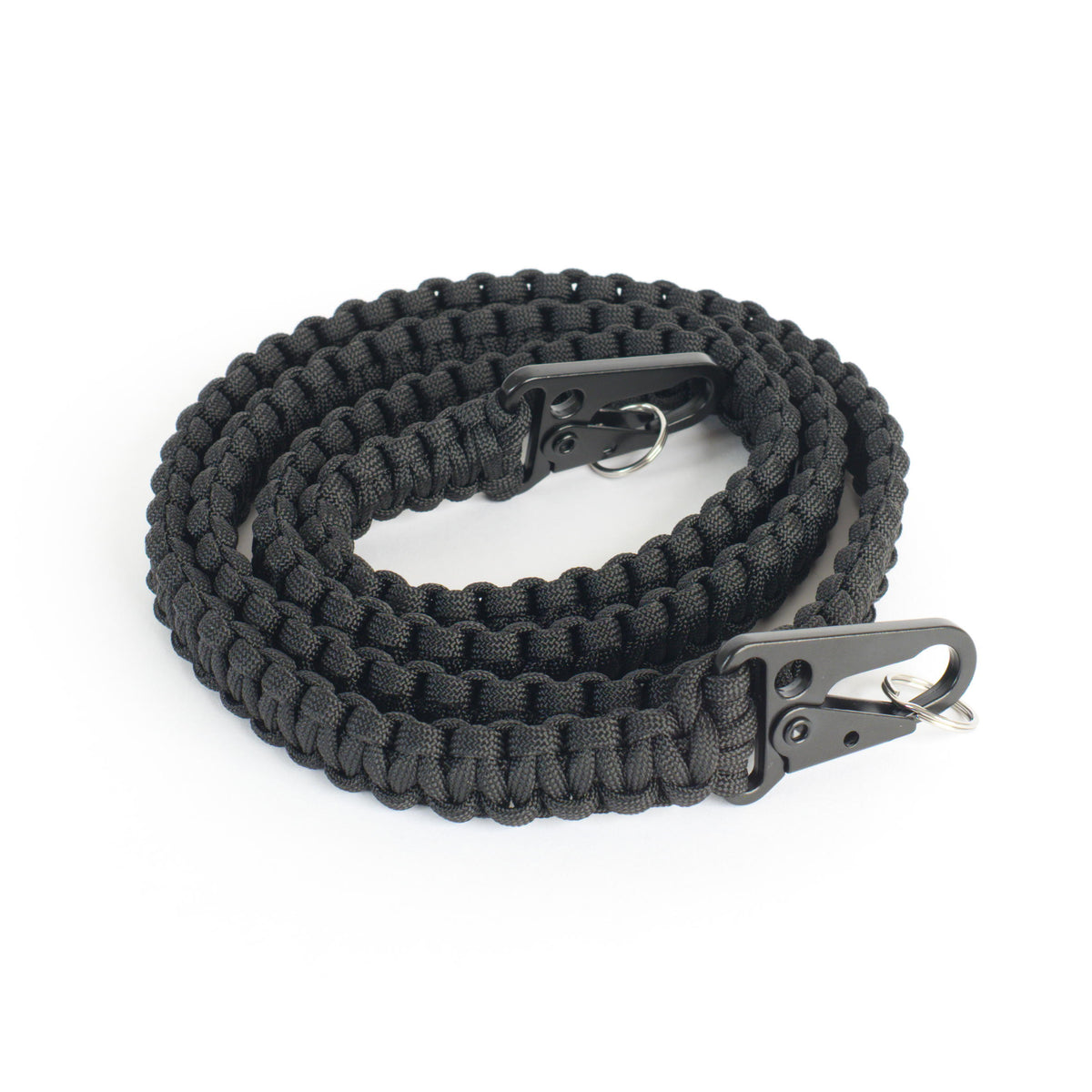 A coiled black paracord sling strap with black metal snap hooks shown on a plain white background.