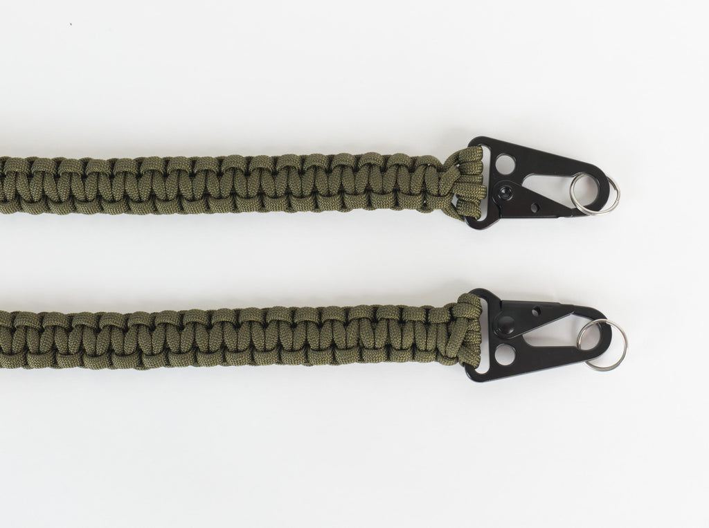 Two olive green paracord lanyards with black metal clip attachments and silver key rings, laid flat on a white background.