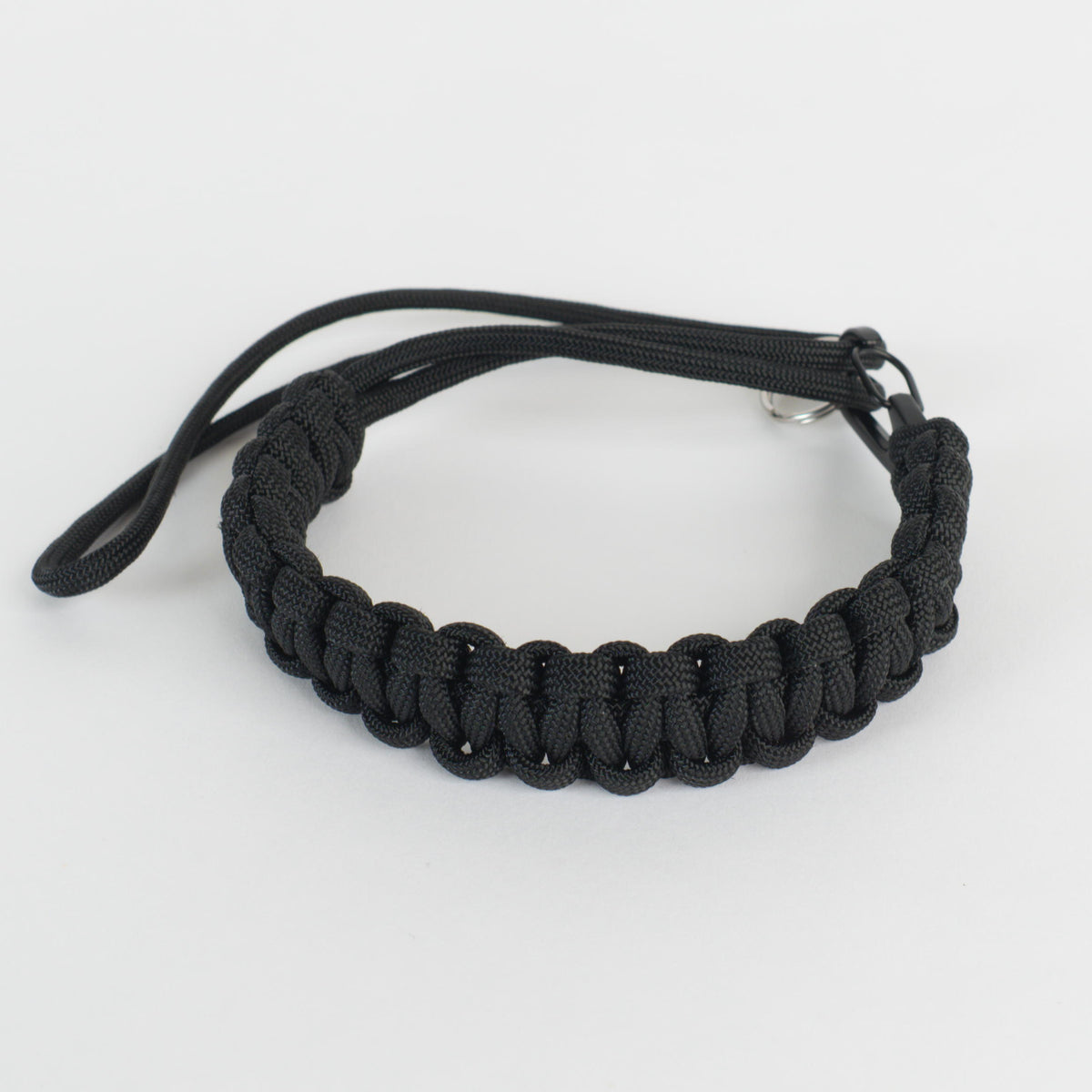A black paracord bracelet with a silver metal clasp, shown on a plain white background.