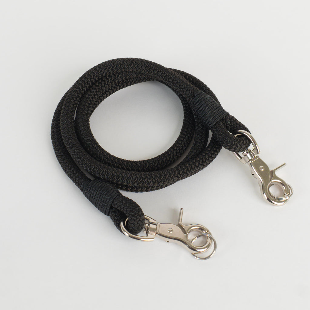 A black rope strap with silver metal lobster clasp ends, coiled on a light gray background.