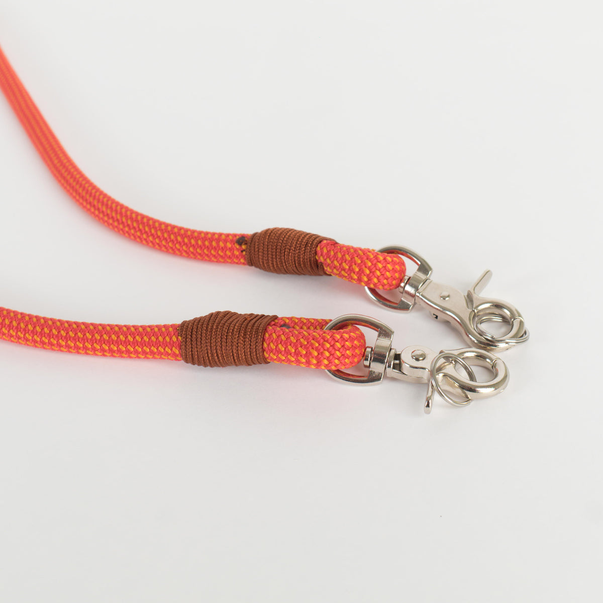 Two ends of a rope strap with burnt orange wrapped ends and silver metal lobster clasps, photographed on a clean white background.